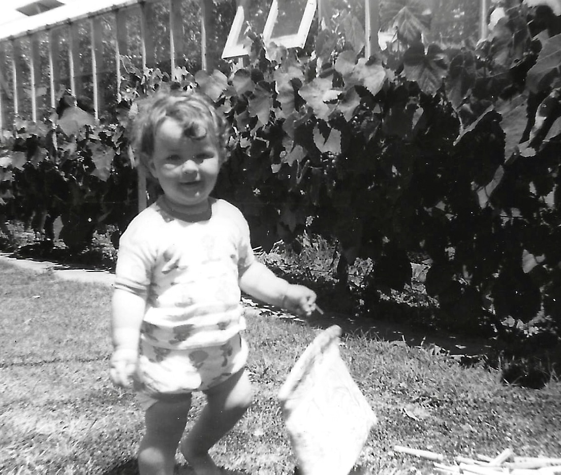 Black and white image of a child walking on a lawn