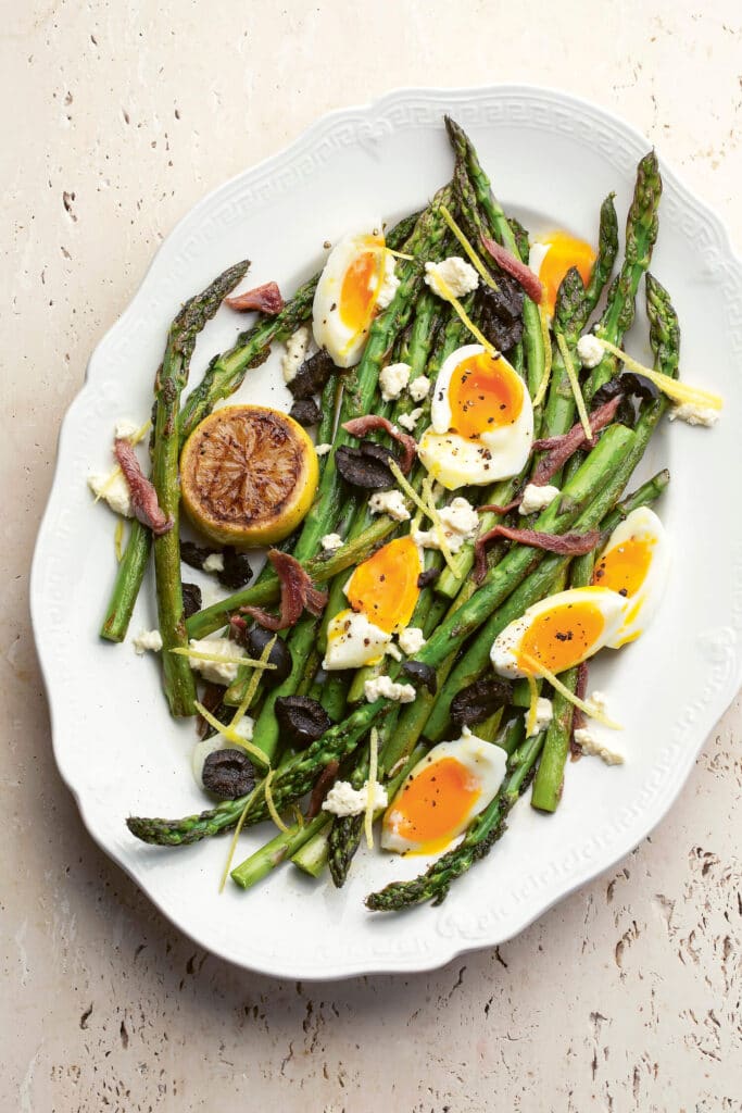 Oval plate of grilled asparagus with soft boiled egg segments
