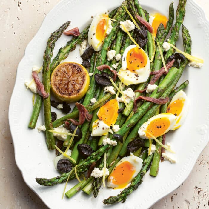 Oval plate of grilled asparagus with soft boiled egg segments