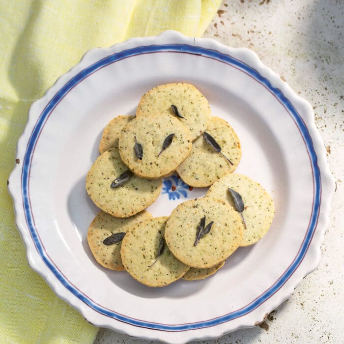 A plate of savoury herb shortbread with a sage leaf on top of each
