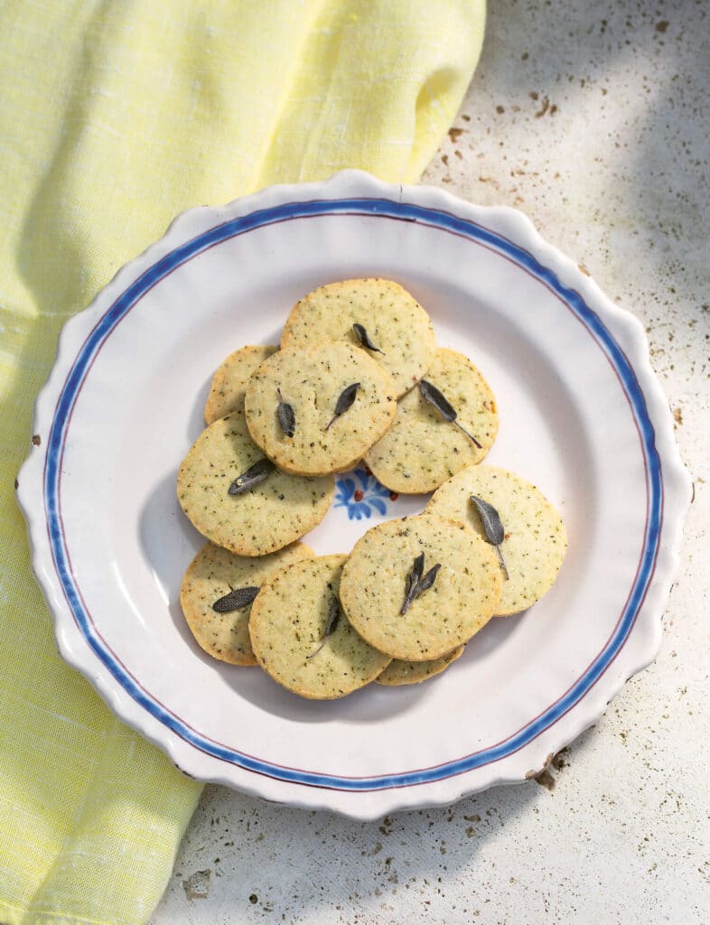 A plate of savoury herb shortbread with a sage leaf on top of each