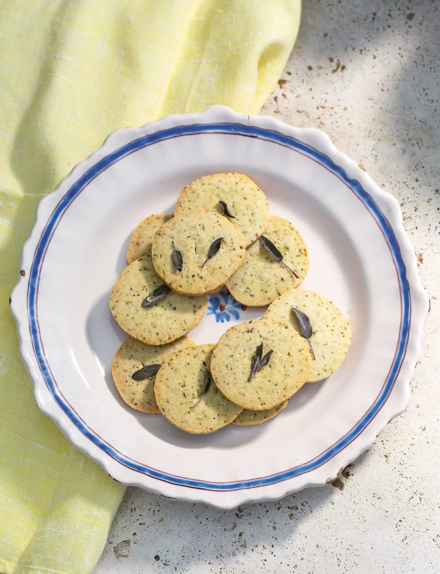A plate of savoury herb shortbread with a sage leaf on top of each