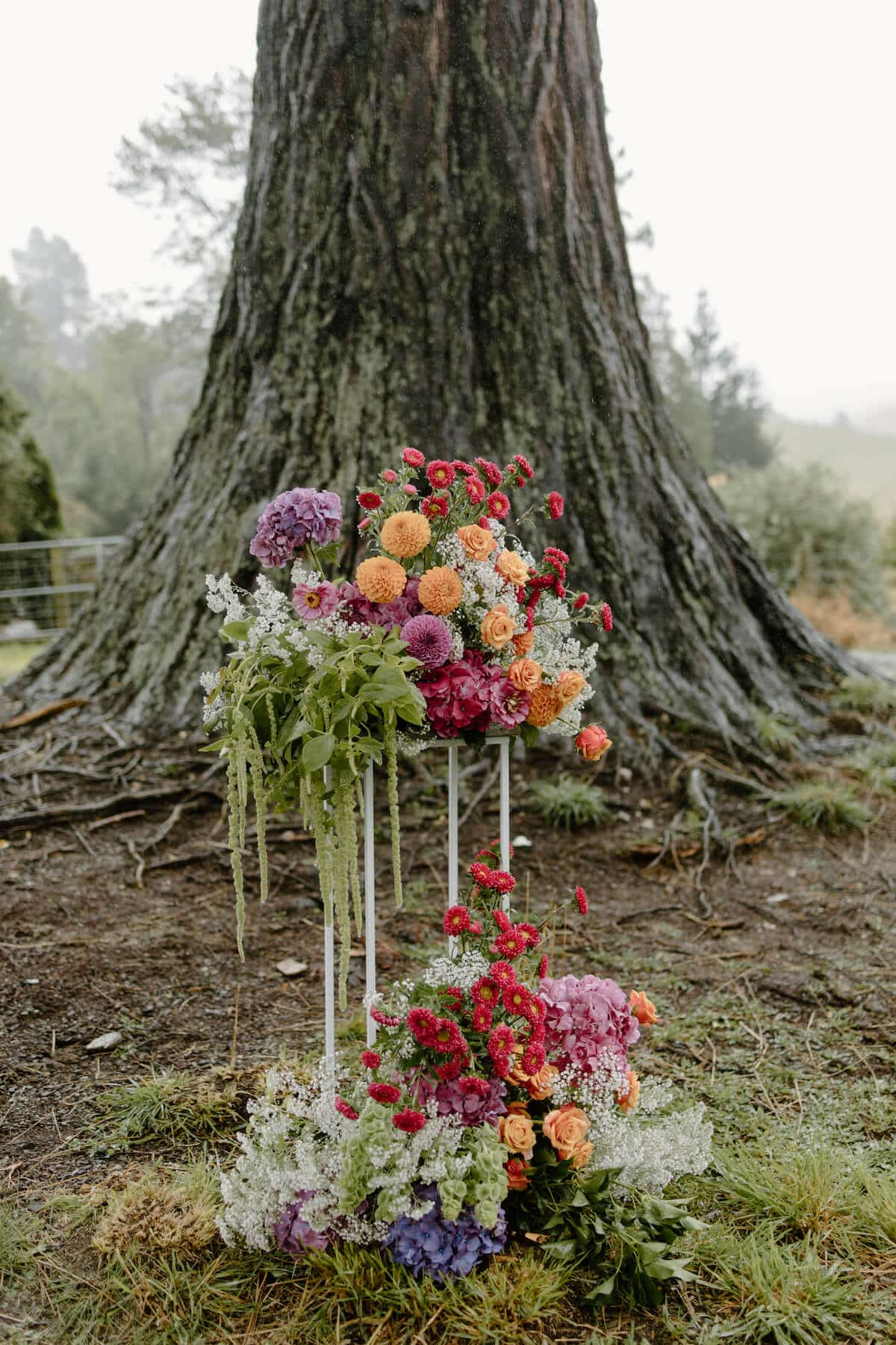 A floral arrangement in front of a thick tree trunk