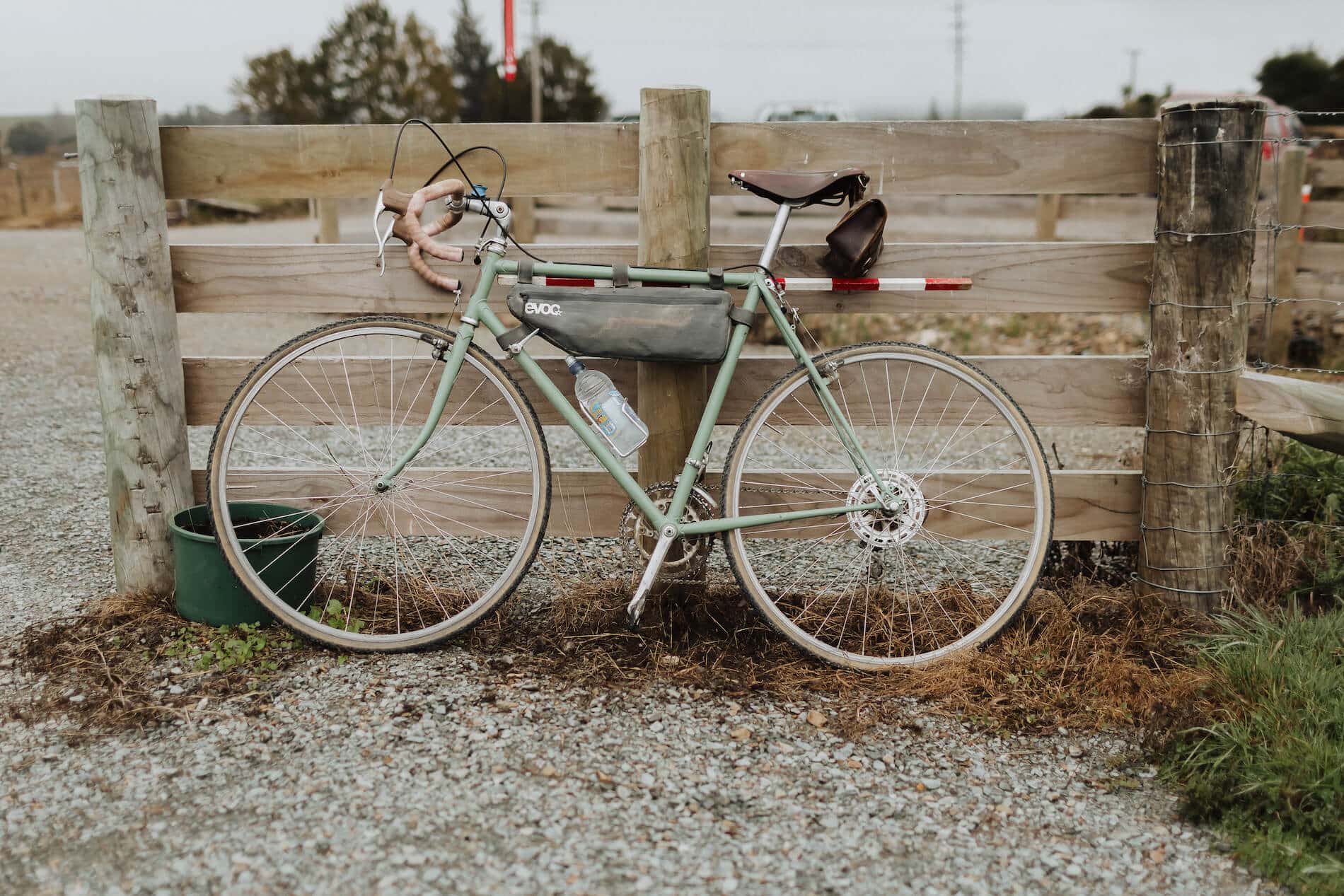 Green bicycle leaning against a wooden fence