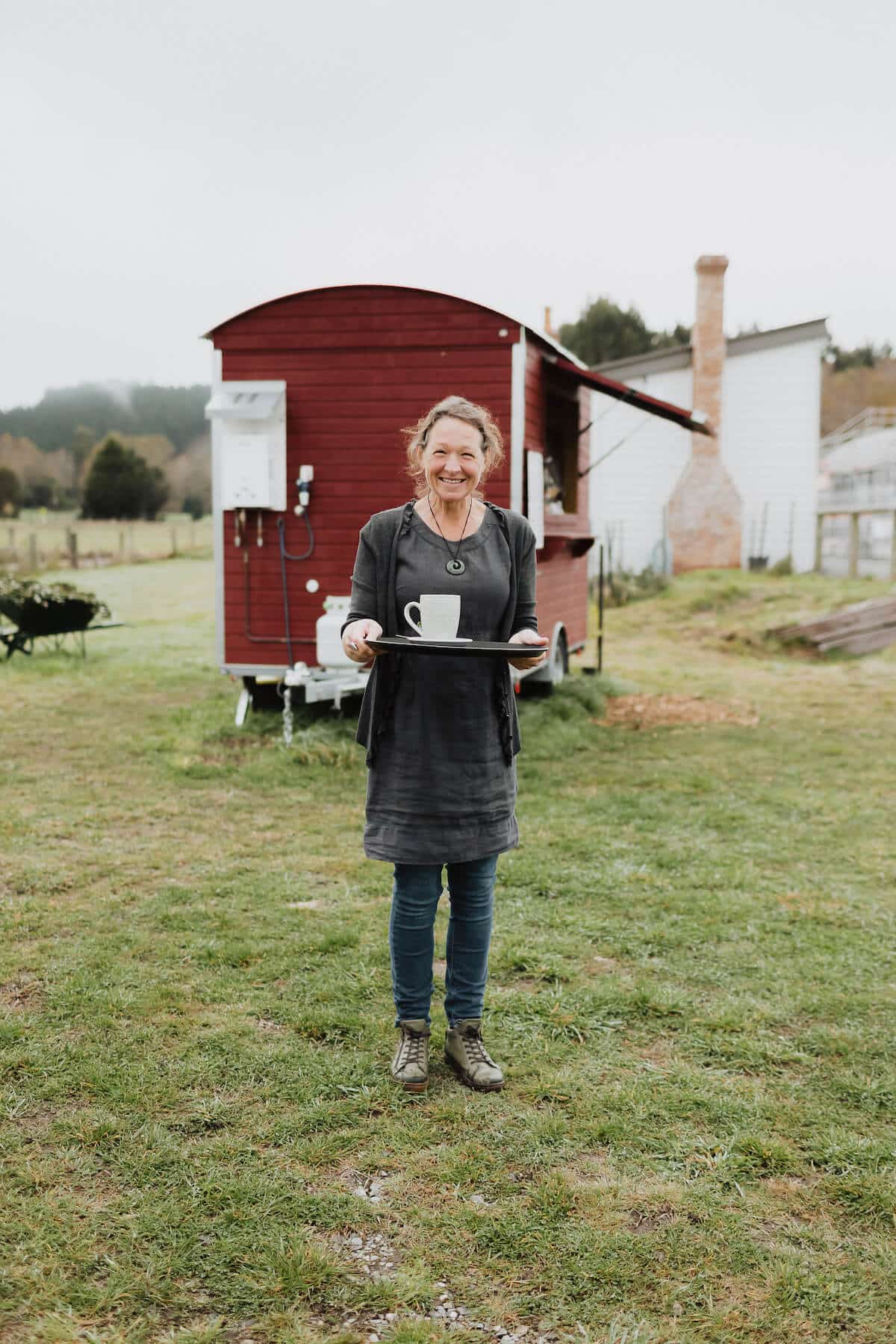 Woman holding a coffee mug on a tray, outside little red coffee cart