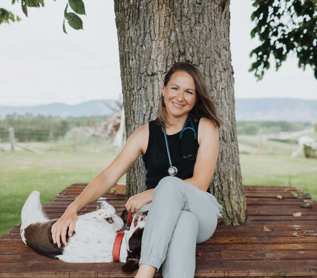 Woman sits in front of a tree with a dog