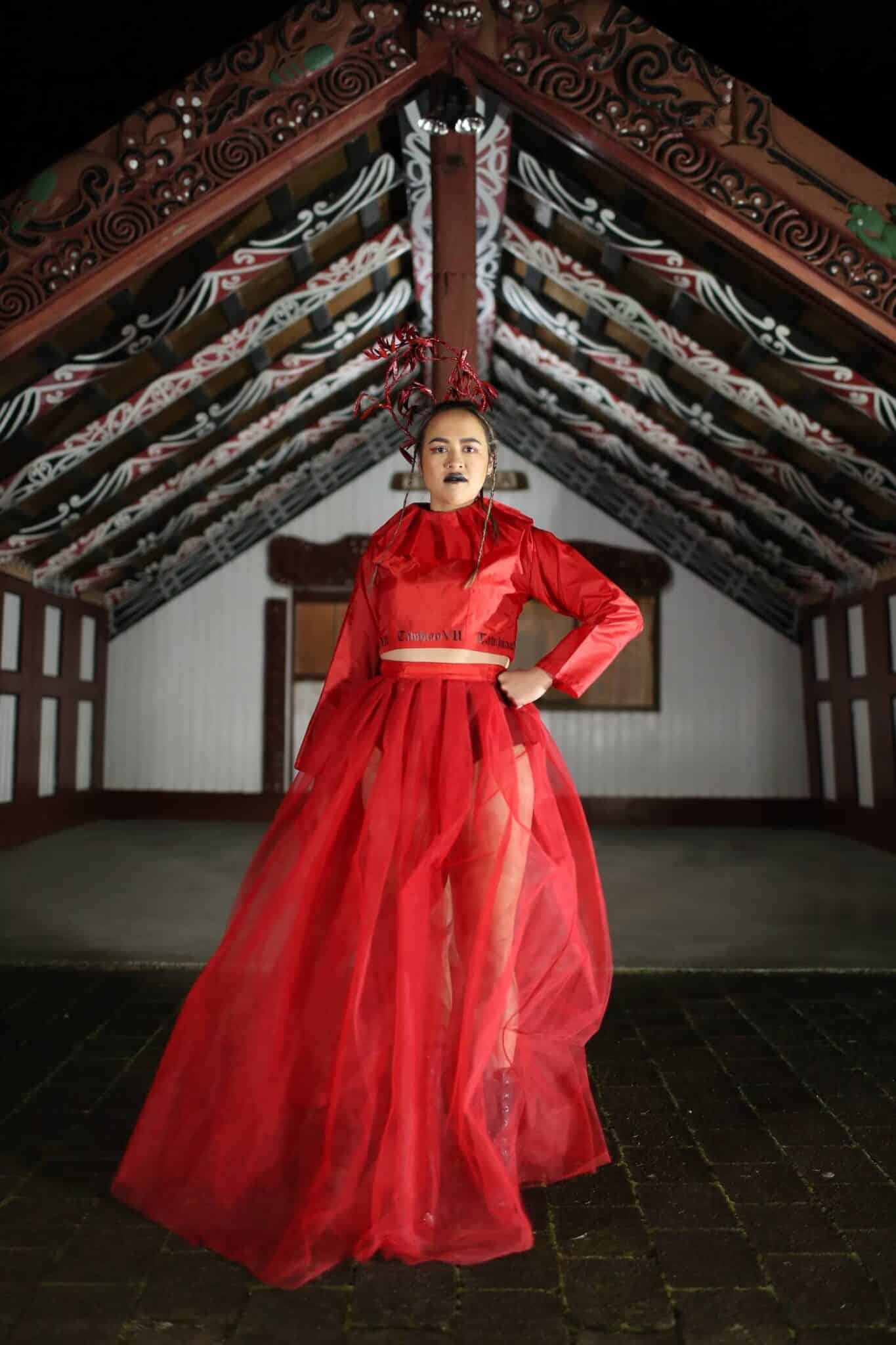 Woman modelling mahi raranga in front of a marae