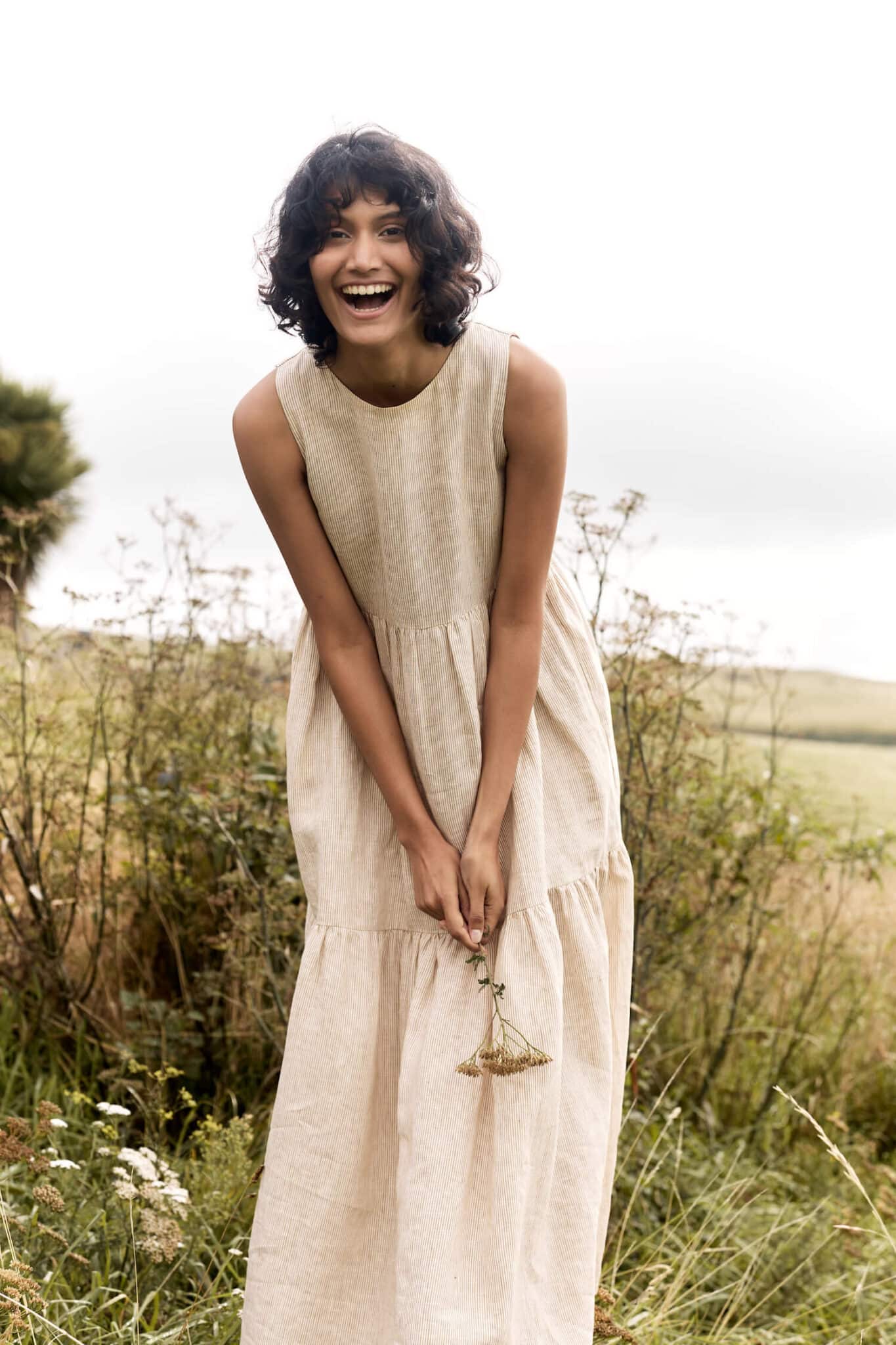 Woman in brown dress bends slightly as she laughs.