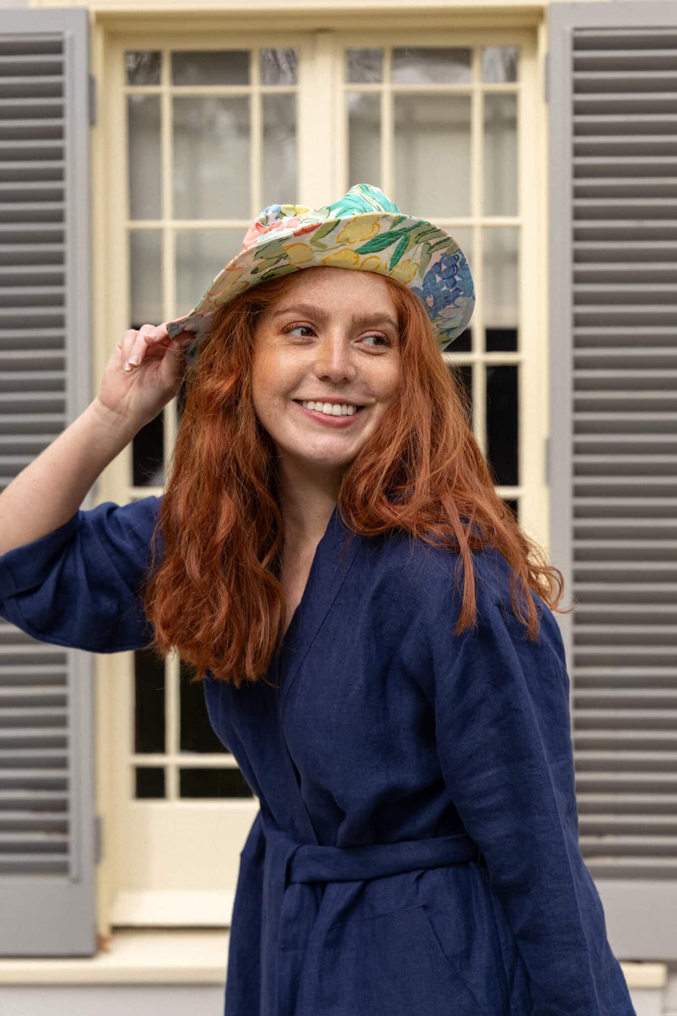 Woman models sunhat and dress in front of The Elms heritage house in Tauranga