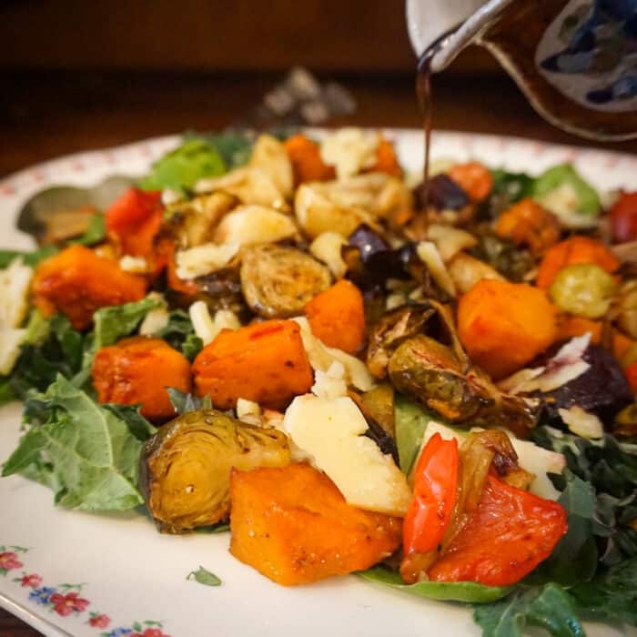 Close-up image of dressing being poured onto a roast vegetable salad.