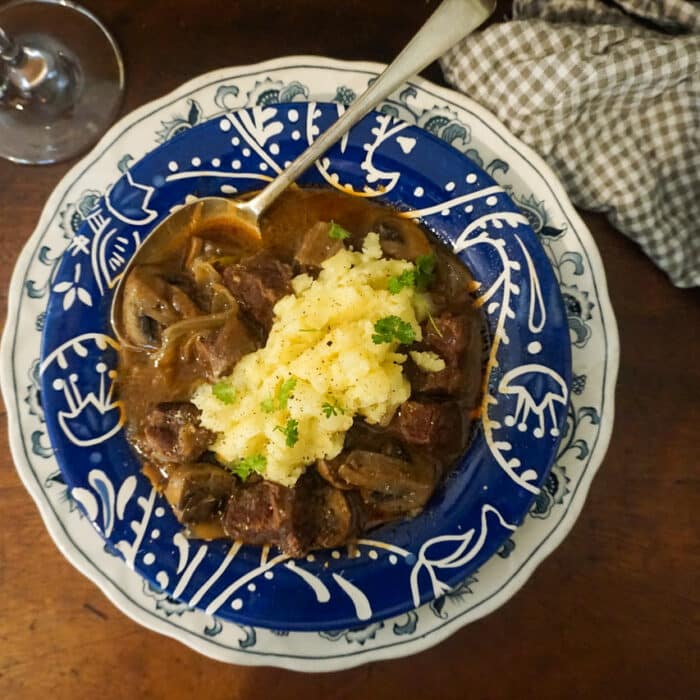 Birdseye of a bowl of beef bourguignon with mashed potato.