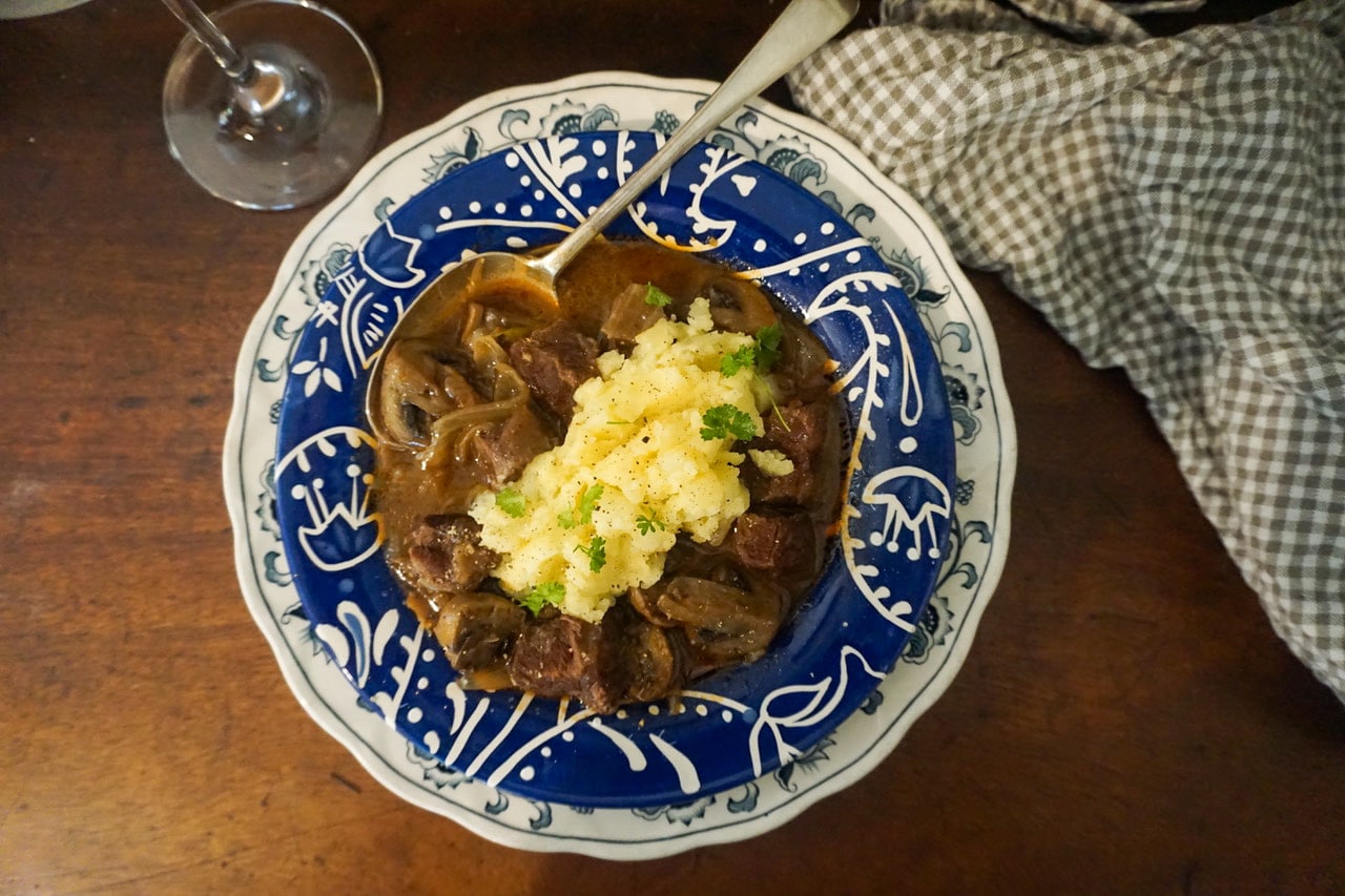 Birdseye of a bowl of beef bourguignon with mashed potato.