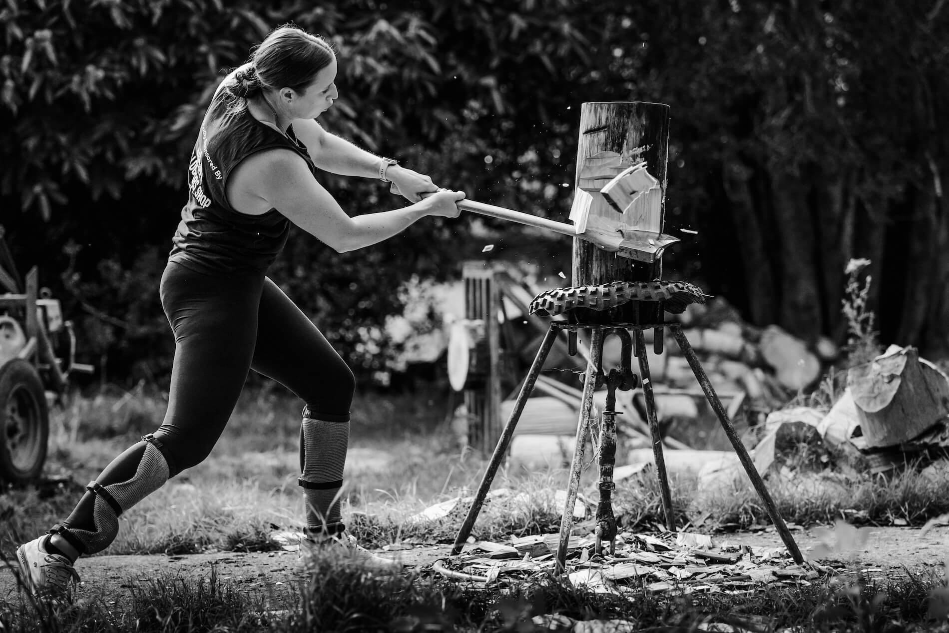 Black and white image of a woman woodchopping with an axe