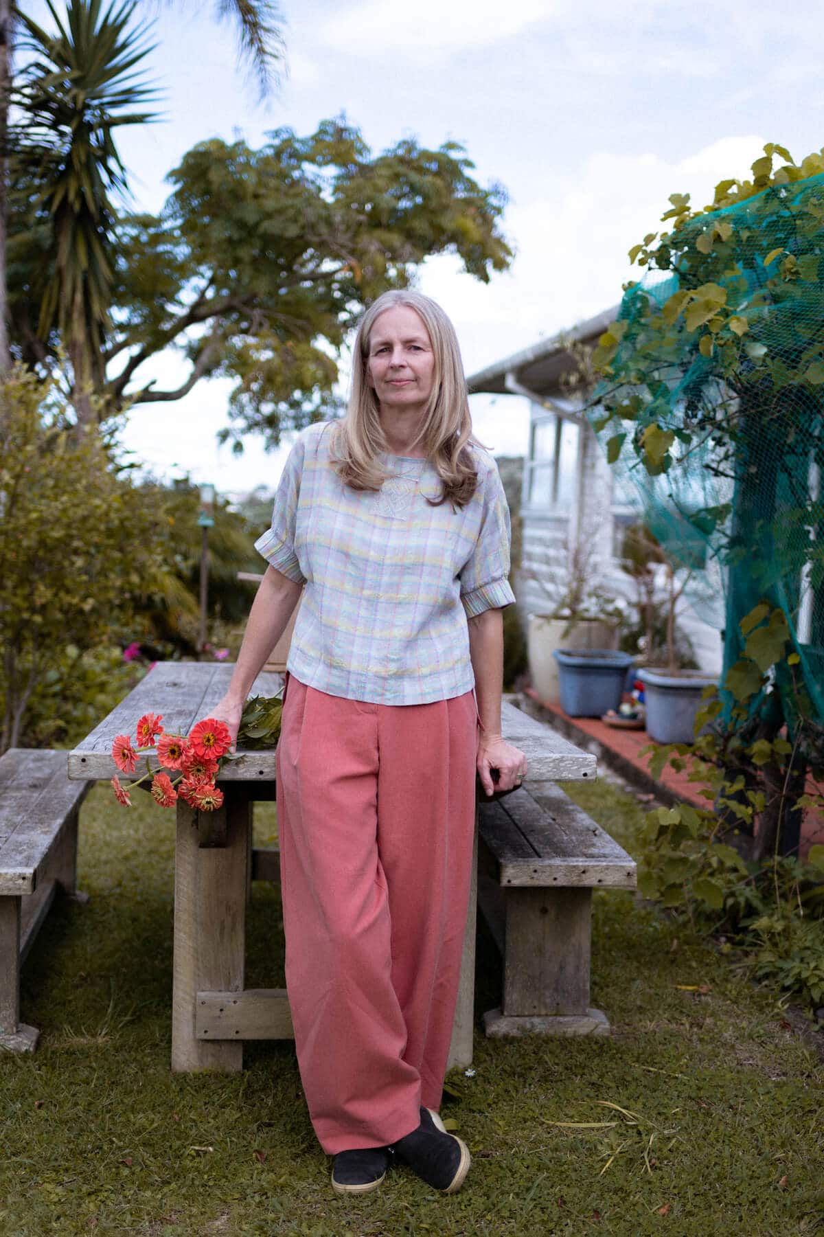 Woman standing in her garden, holding flowers