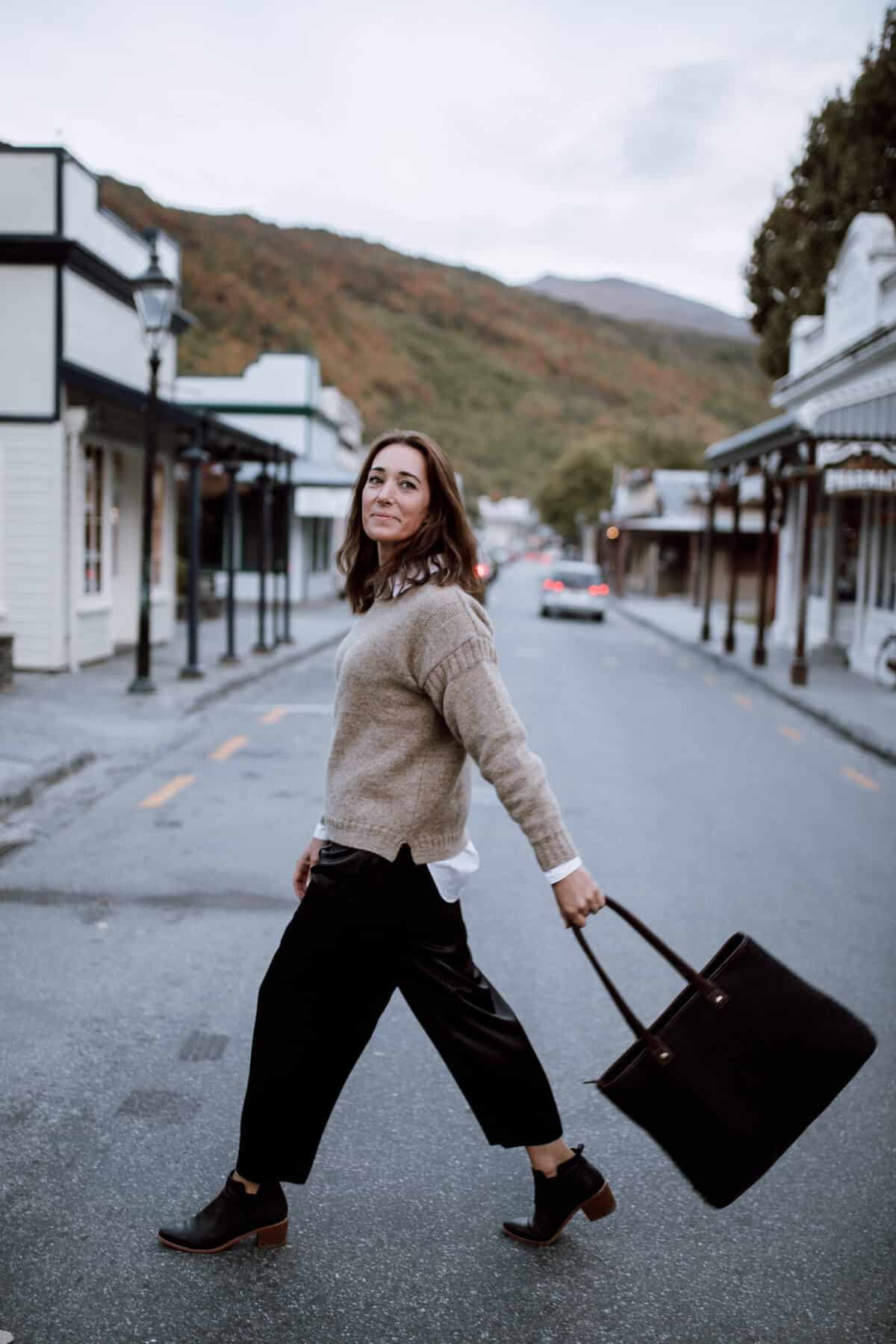Woman in woollen jersey walking across a small street