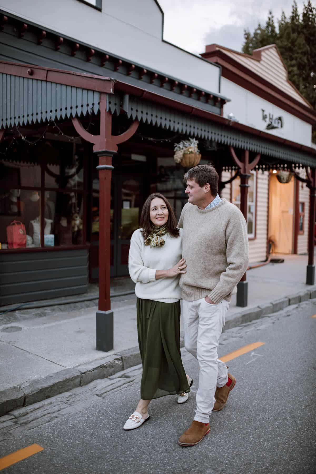 Woman and man in woollen jerseys walking down an historic street