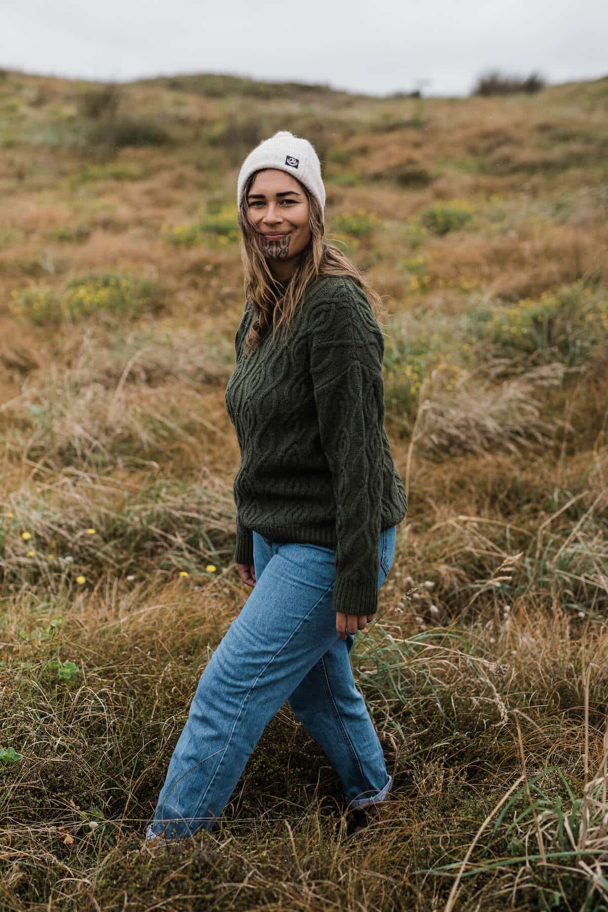 Arpége wearing the Pendeen Cable Neck Crew in Forest, $179.99, Hutton Turn Up Bobble Beanie in Oatmeal, $59.99, and her own denim. 