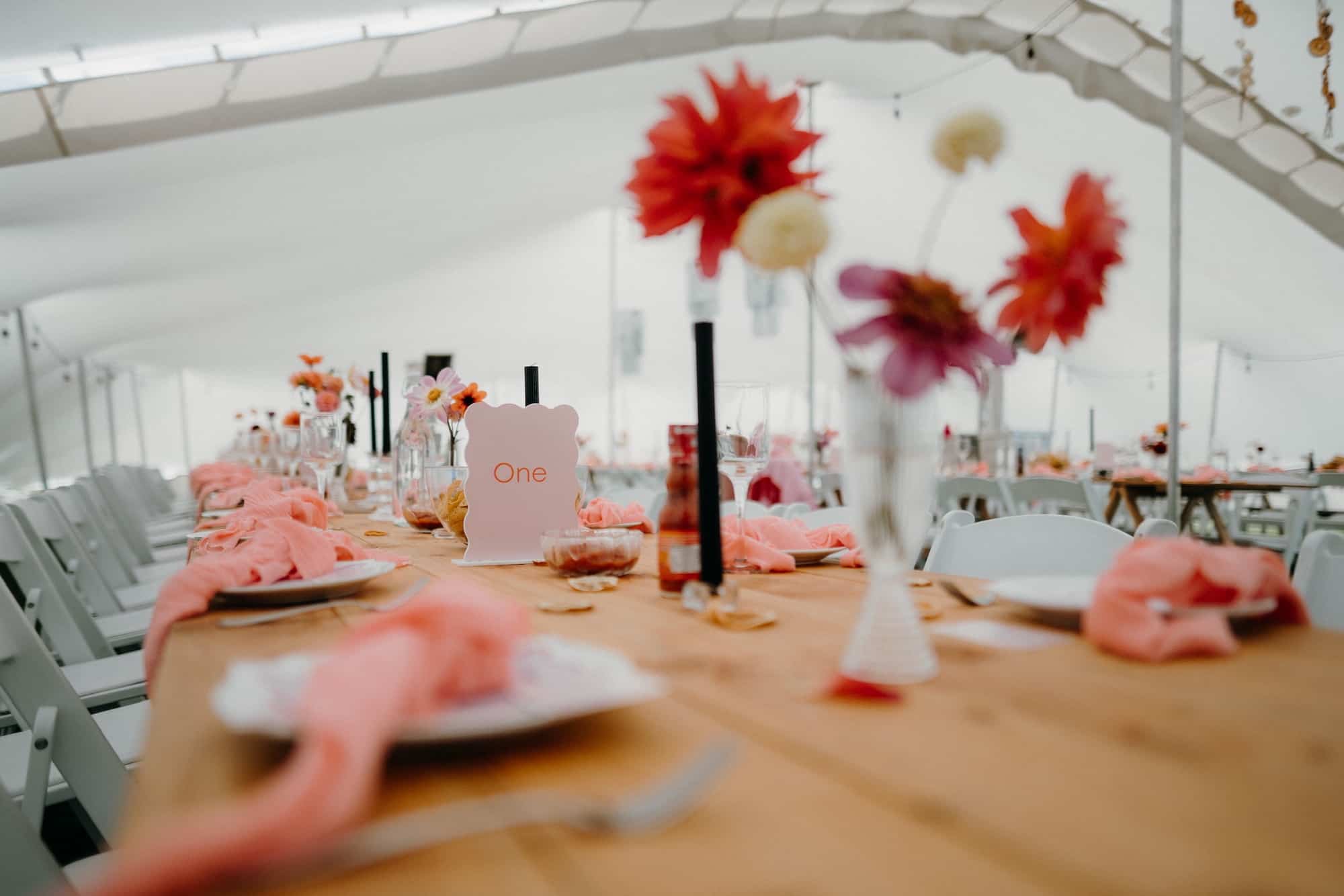 Pink and orange table settings inside a marquee at a wedding in Aparima Riverton