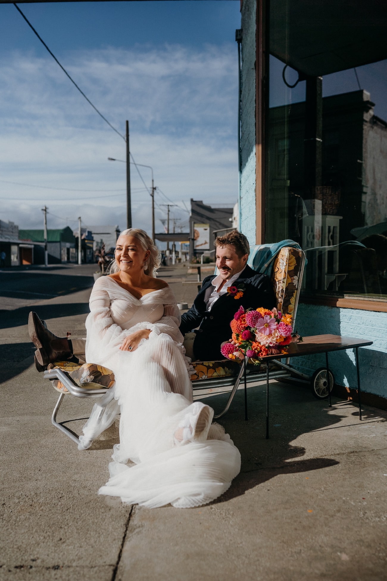 Newlywed couple sits on a retro lounger outside Crib Cafe in Aparima Riverton