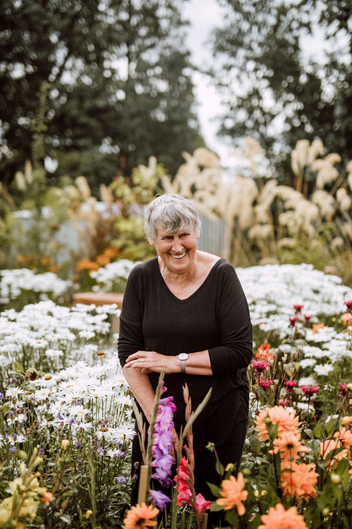 Woman stands in her garden amongst flowers