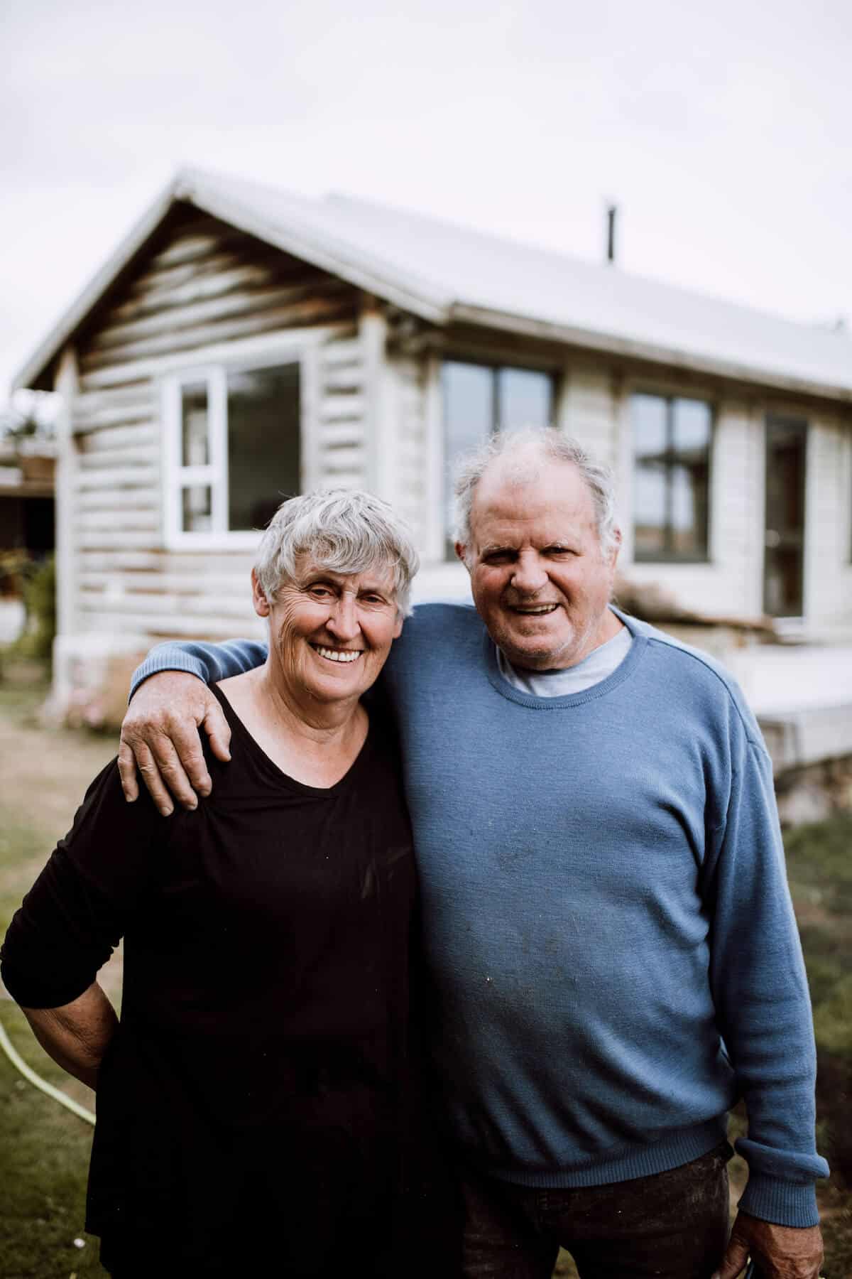 Female and male couple stand outside their house