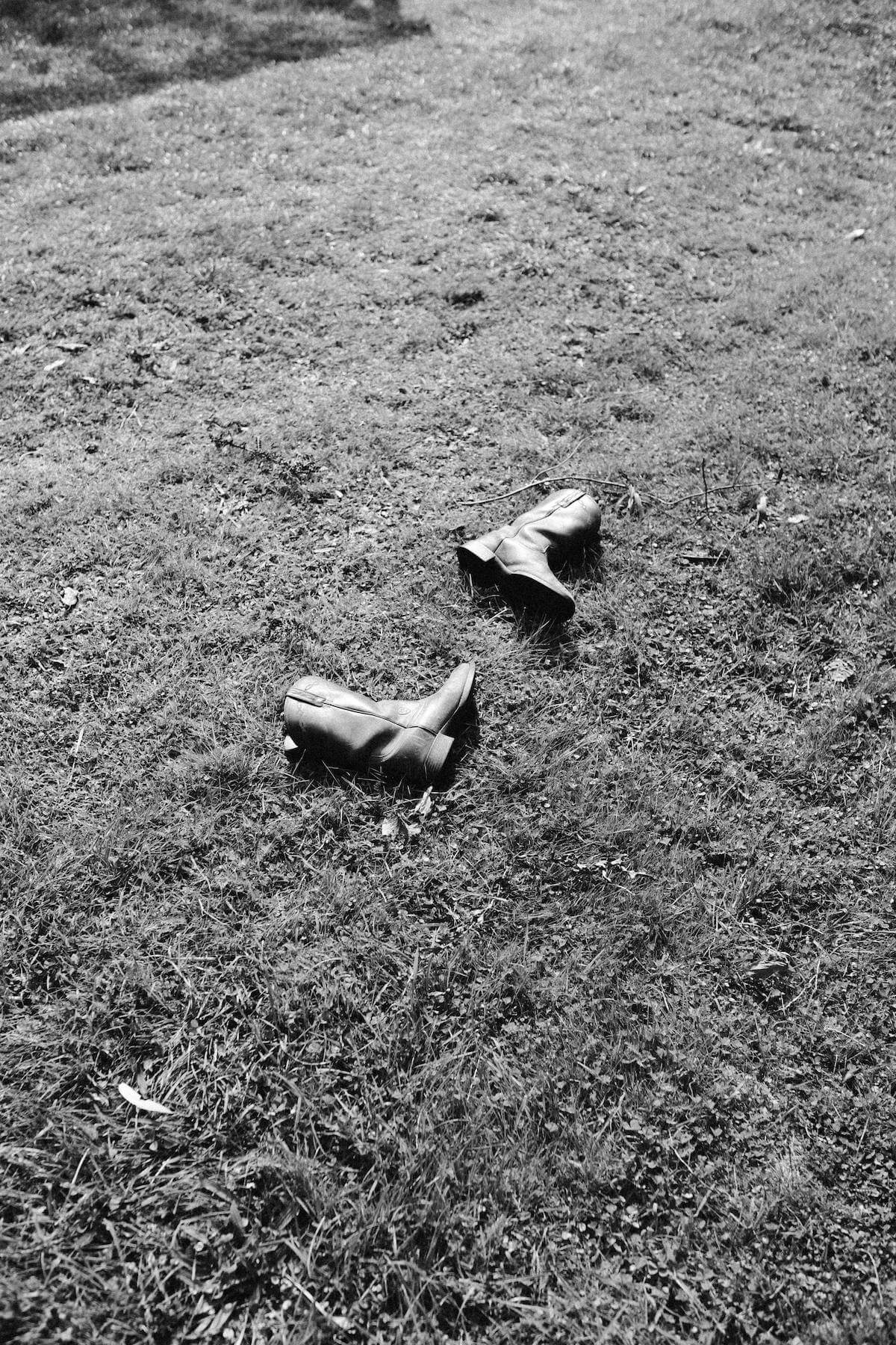 Black and white image of cowgirl boots on a lawn.