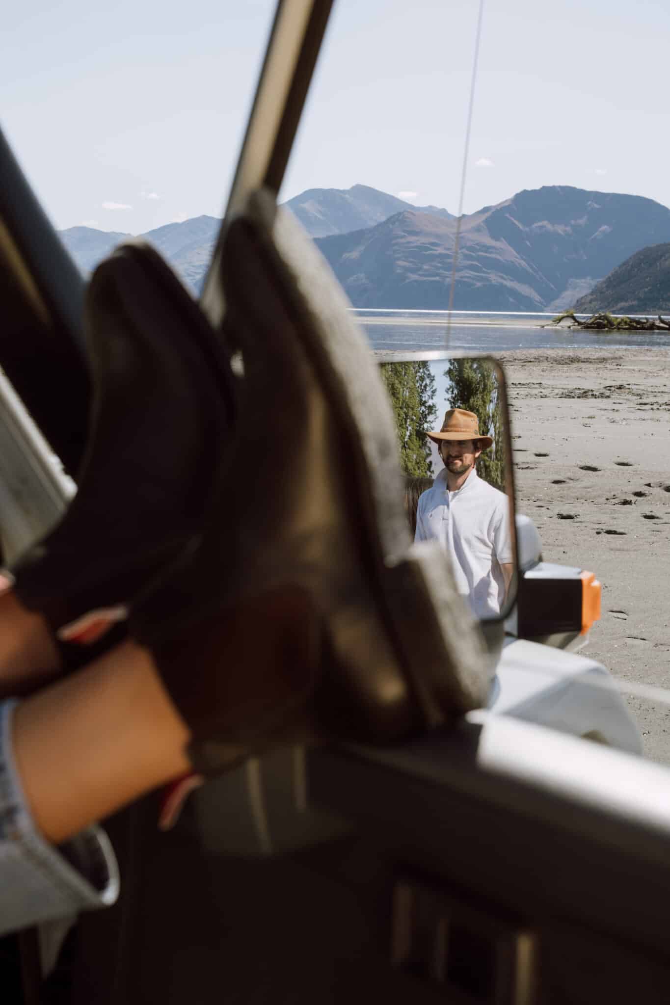 A pair of brown booted feet rest on a car's door frame.