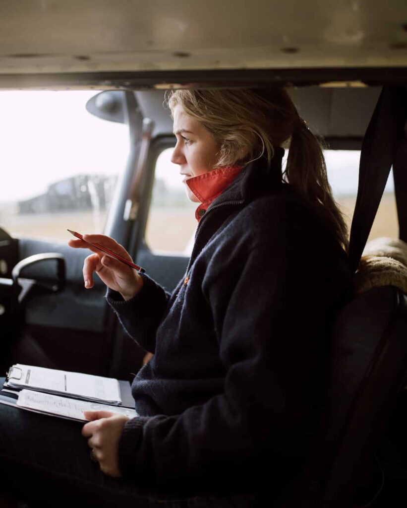 Woman sits in the cockpit of a small plane as she takes notes