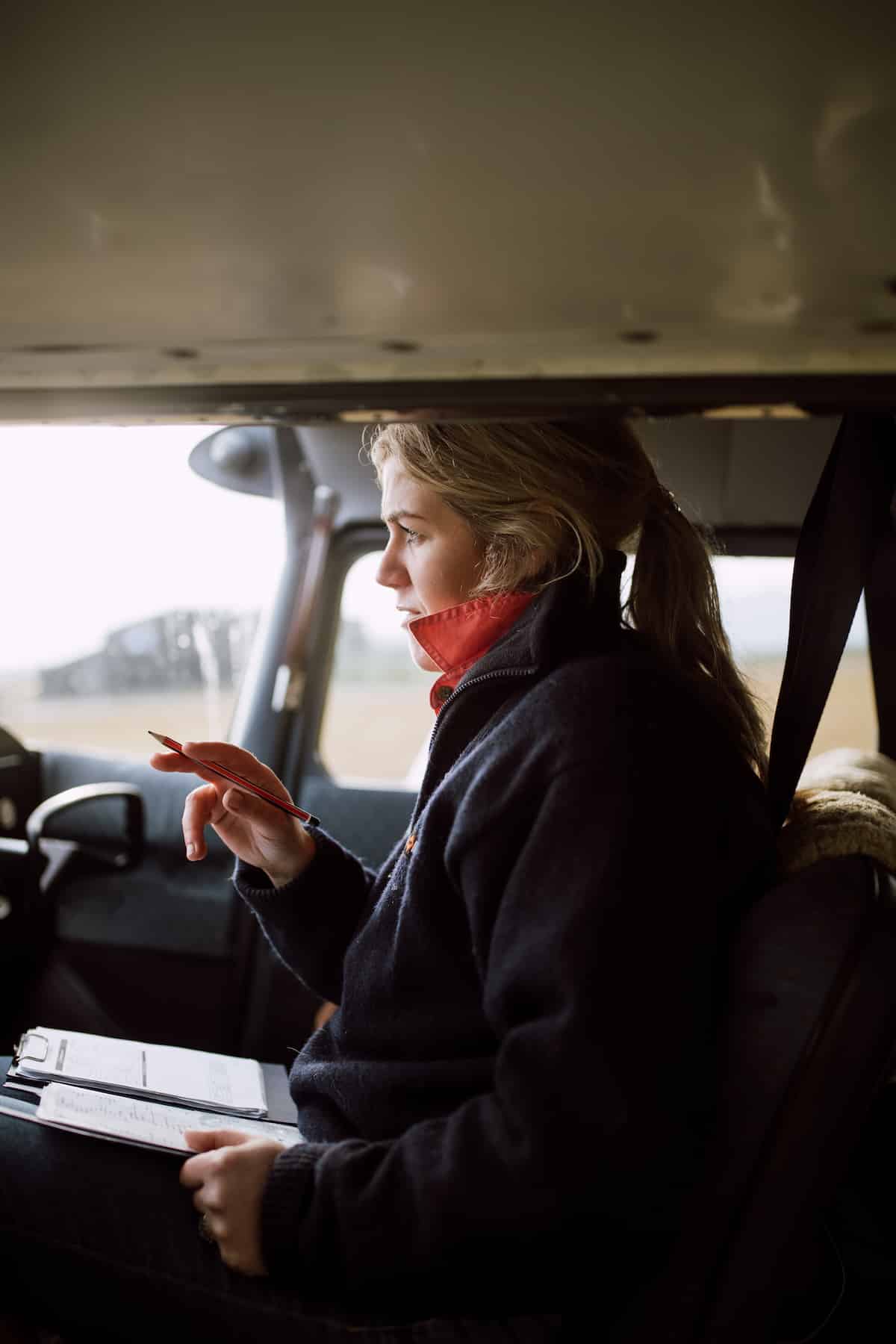 Woman sits in the cockpit of a small plane as she takes notes