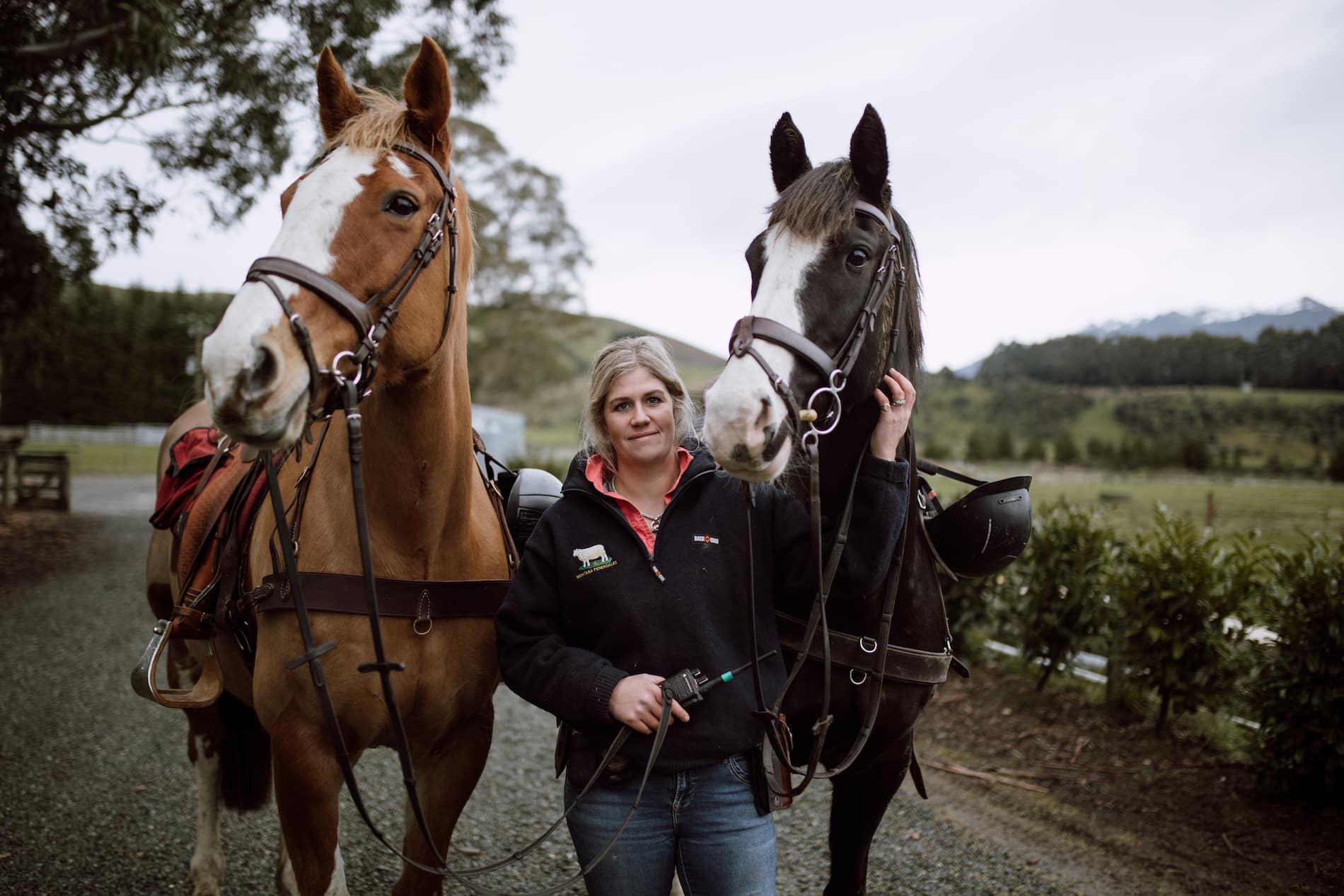 Woman stands in between two horses