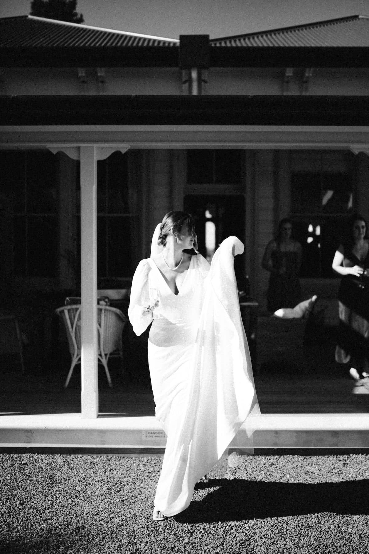 Black and white image of a bride stepping across a lawn.