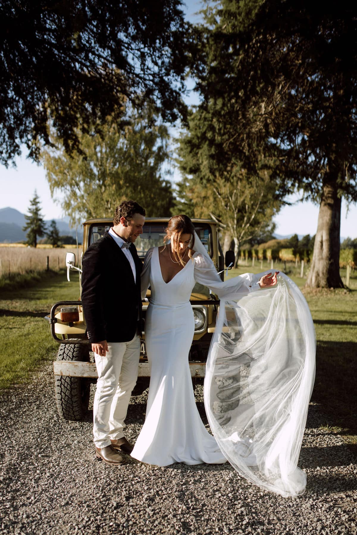 Newlyweds pose in front of a vintage Toyota Land Cruiser