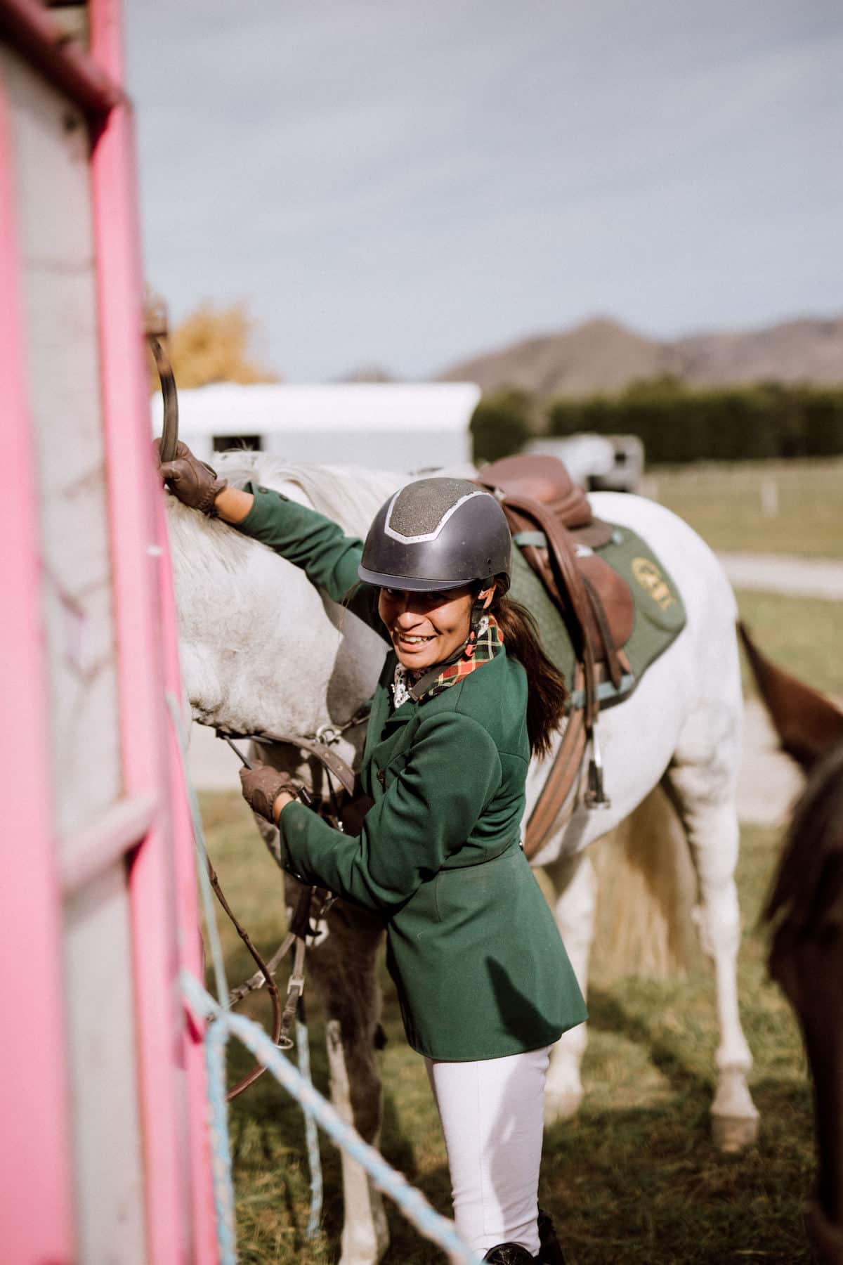 Female showjumper saddling her horse