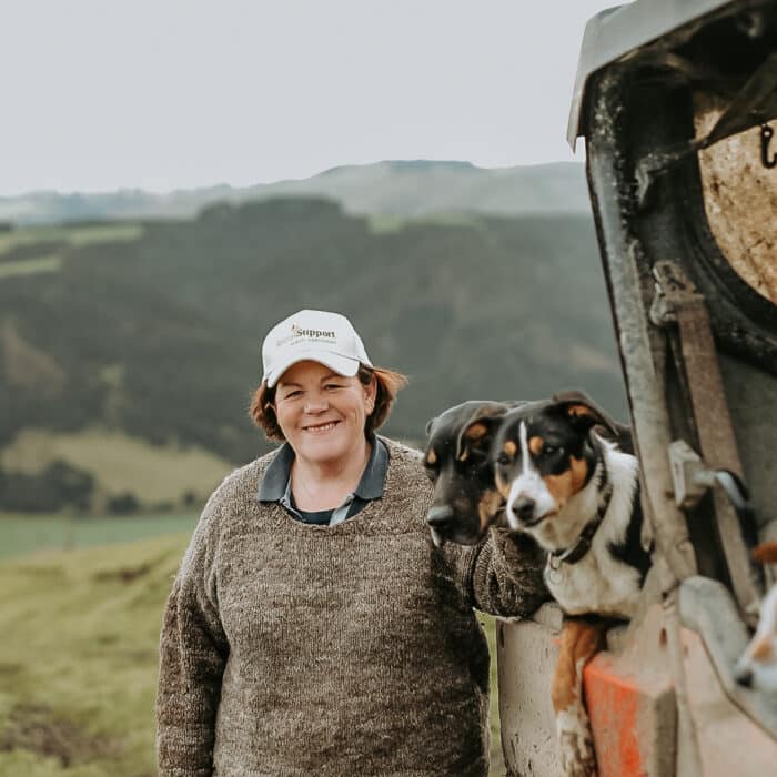 Woman stands beside a muddy farm buggy with two dogs