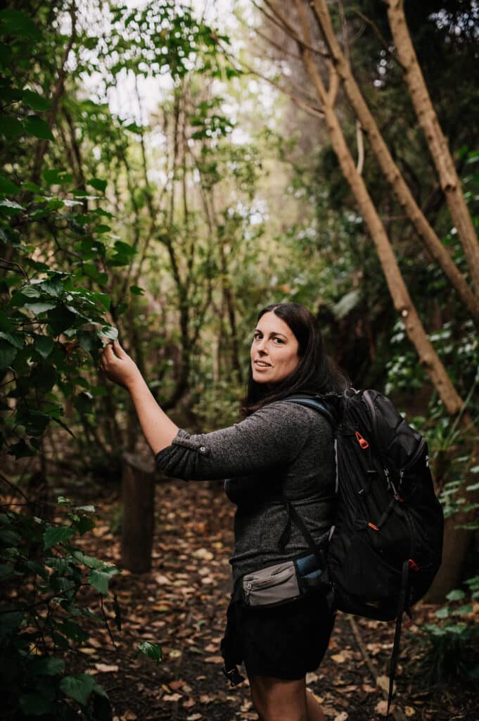 A woman inspects a leaf on a bush walk.