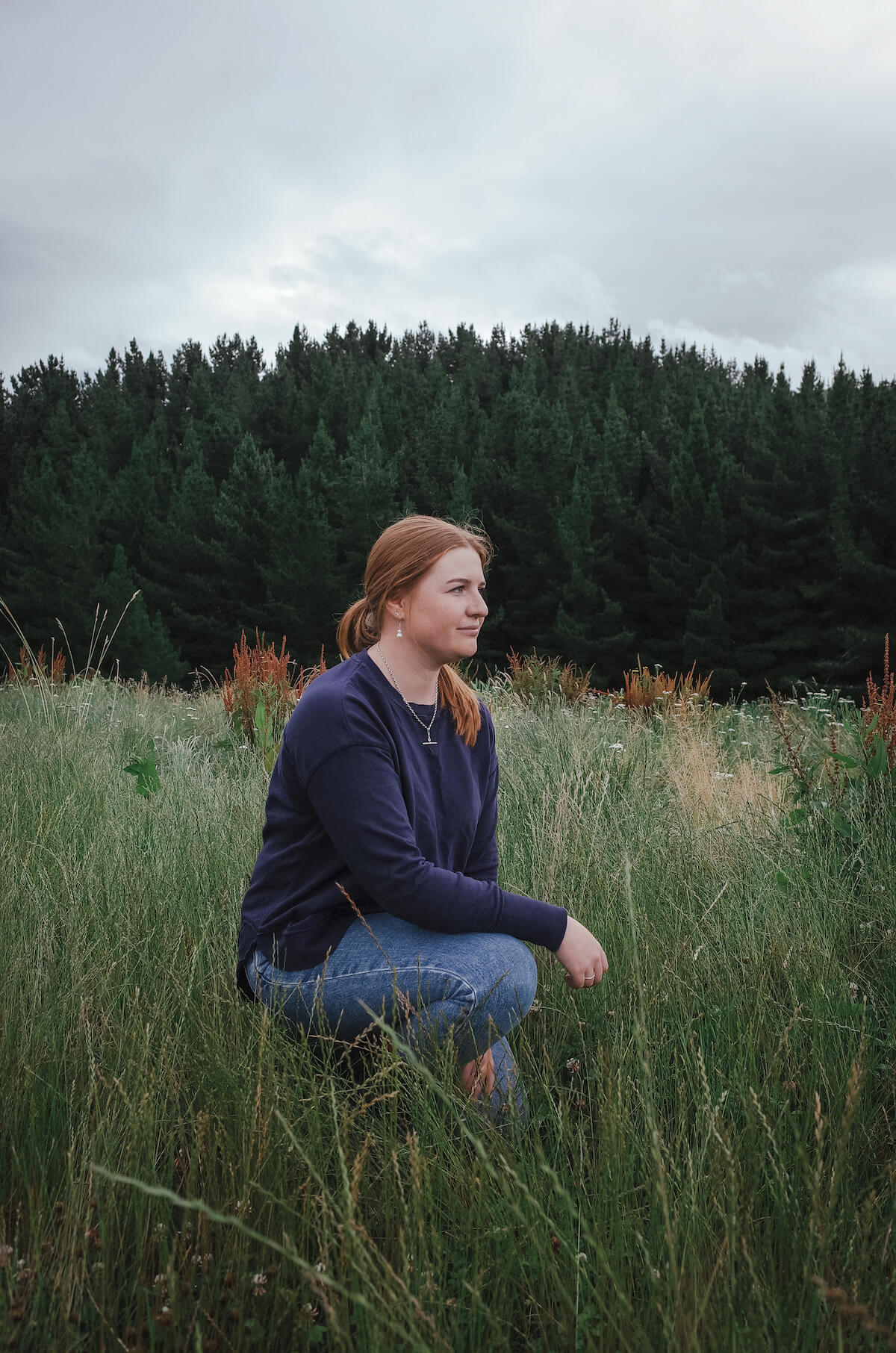 Woman kneels in grassy field