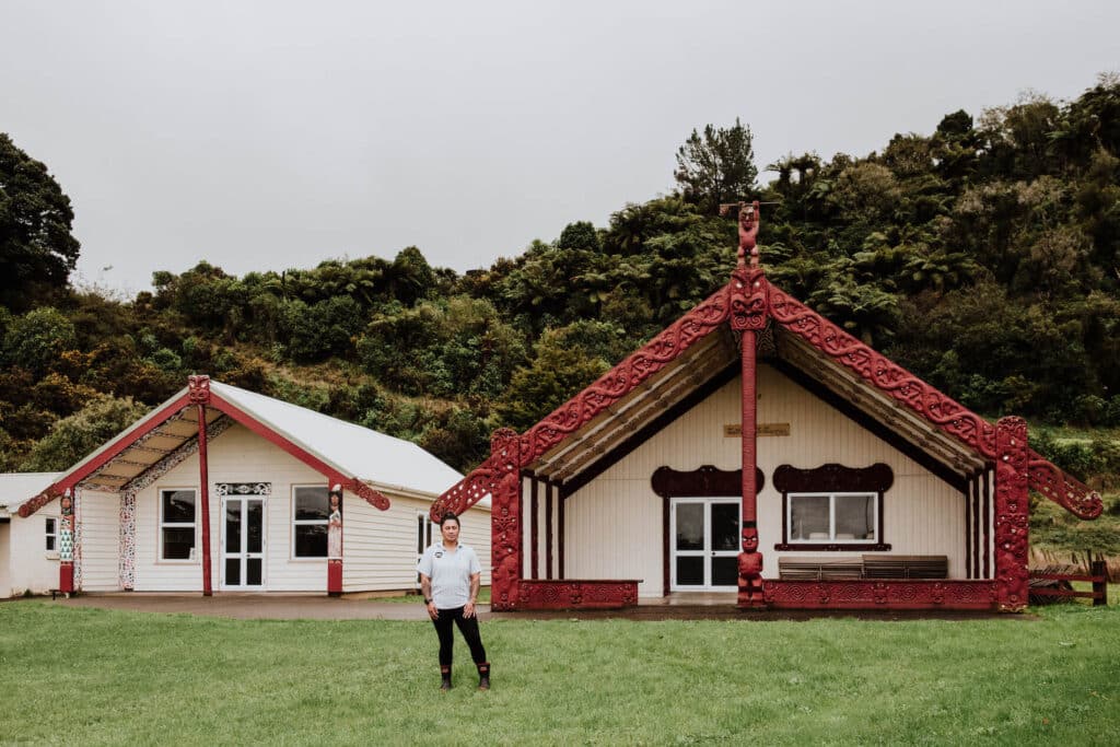 Woman stands in front of her marae.