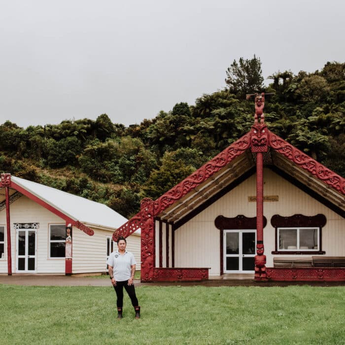 Woman stands in front of her marae.