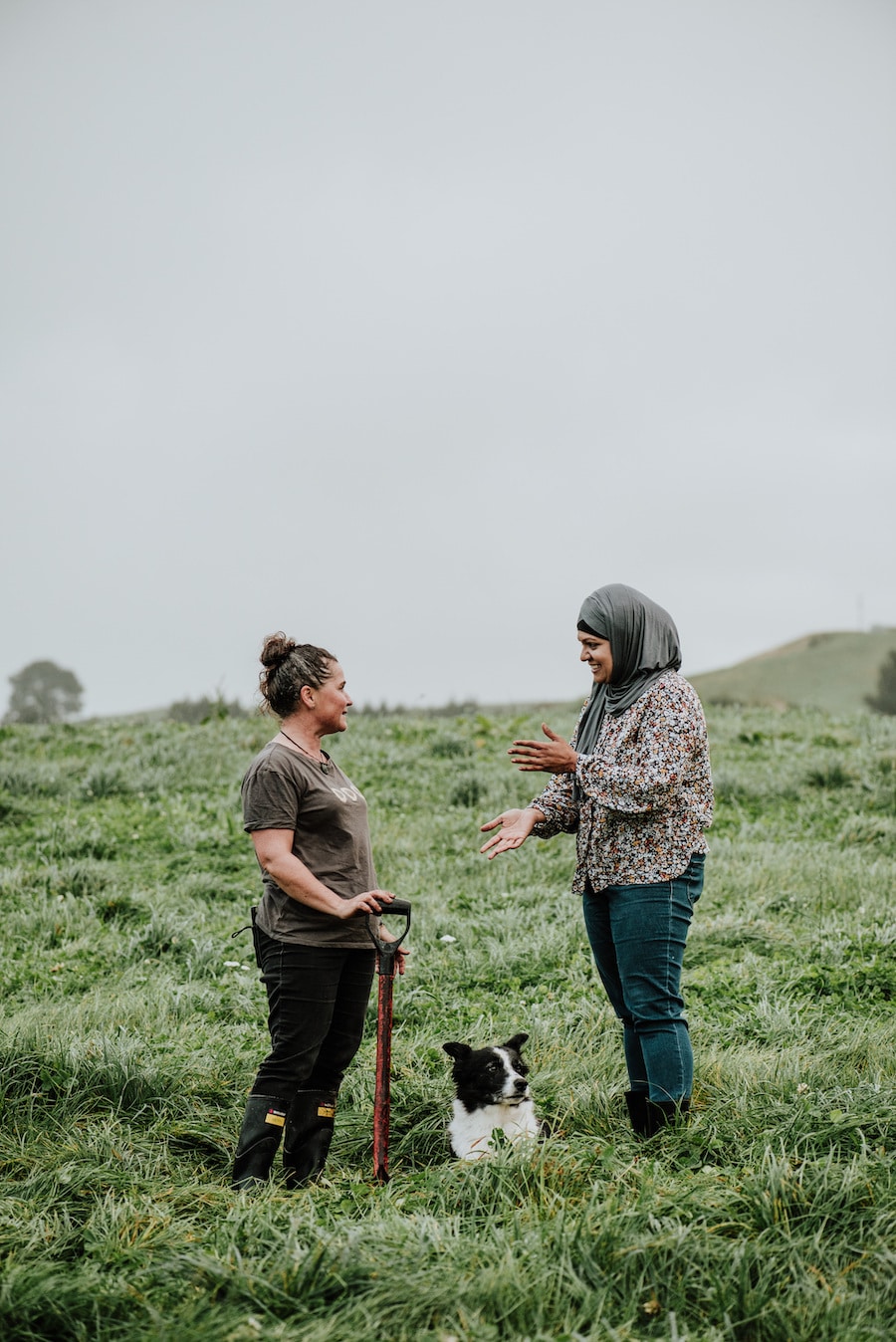 Two women talking in a grassy paddock.