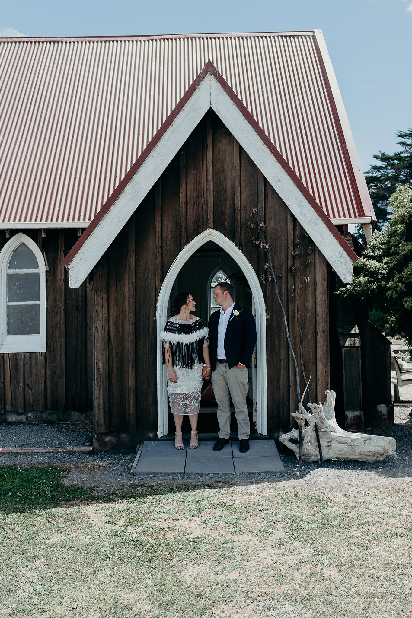 Rachel and Thomas hold hands in front of the marae