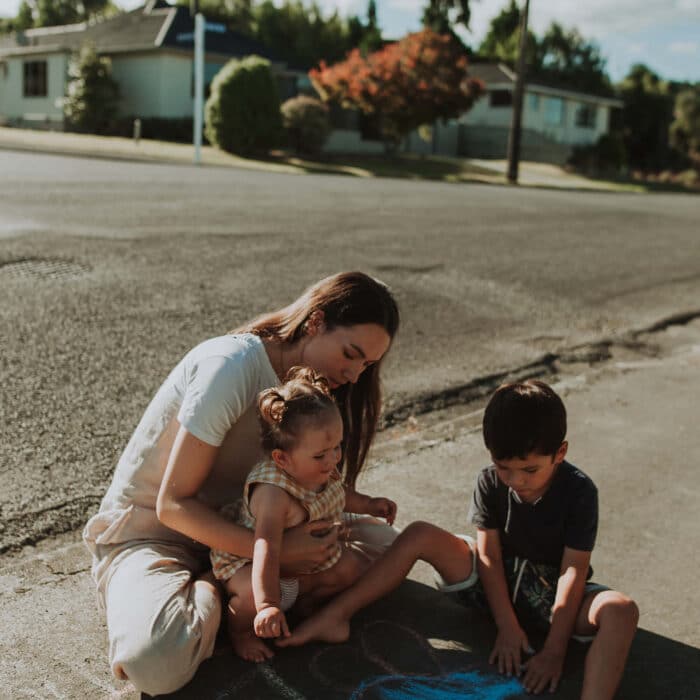 Renee plays with her two young children on the footpath.