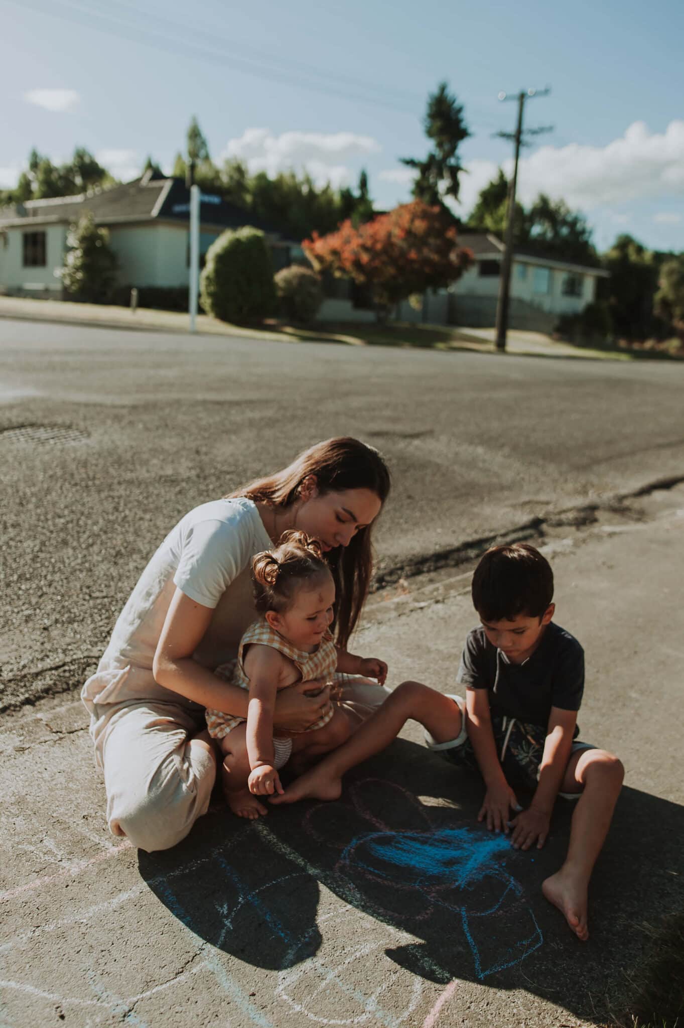 Renee plays with her two young children on the footpath.