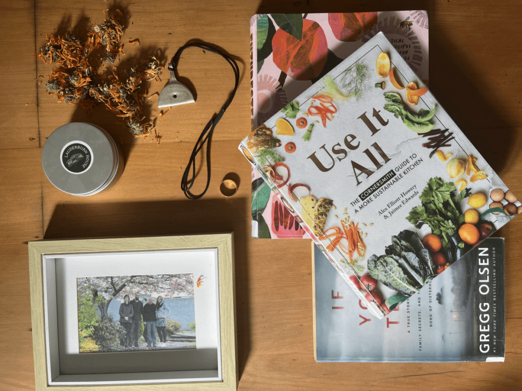 A collection of books, seeds, jewellery and a photograph on a table.