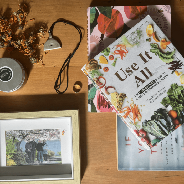 A collection of books, seeds, jewellery and a photograph on a table.
