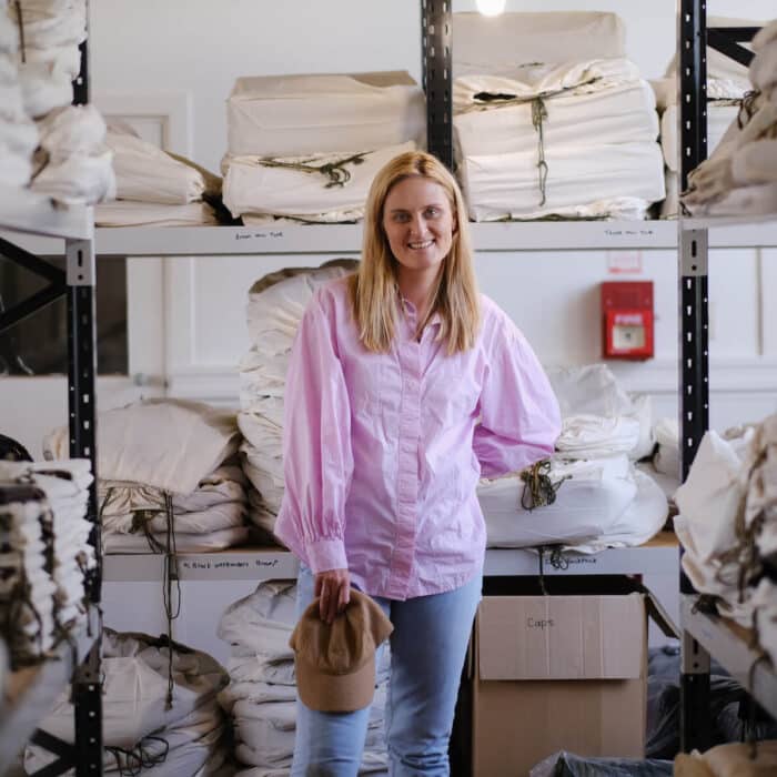 Woman stands in the storeroom of her woollen products shop.