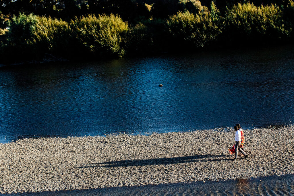 A couple walks beside a river