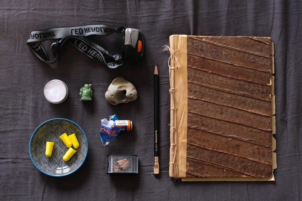 A sketchbook, pencil and miscellaneous bedside table items all laid out.