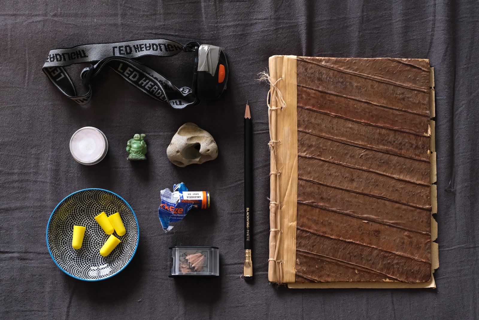 A sketchbook, pencil and miscellaneous bedside table items all laid out.