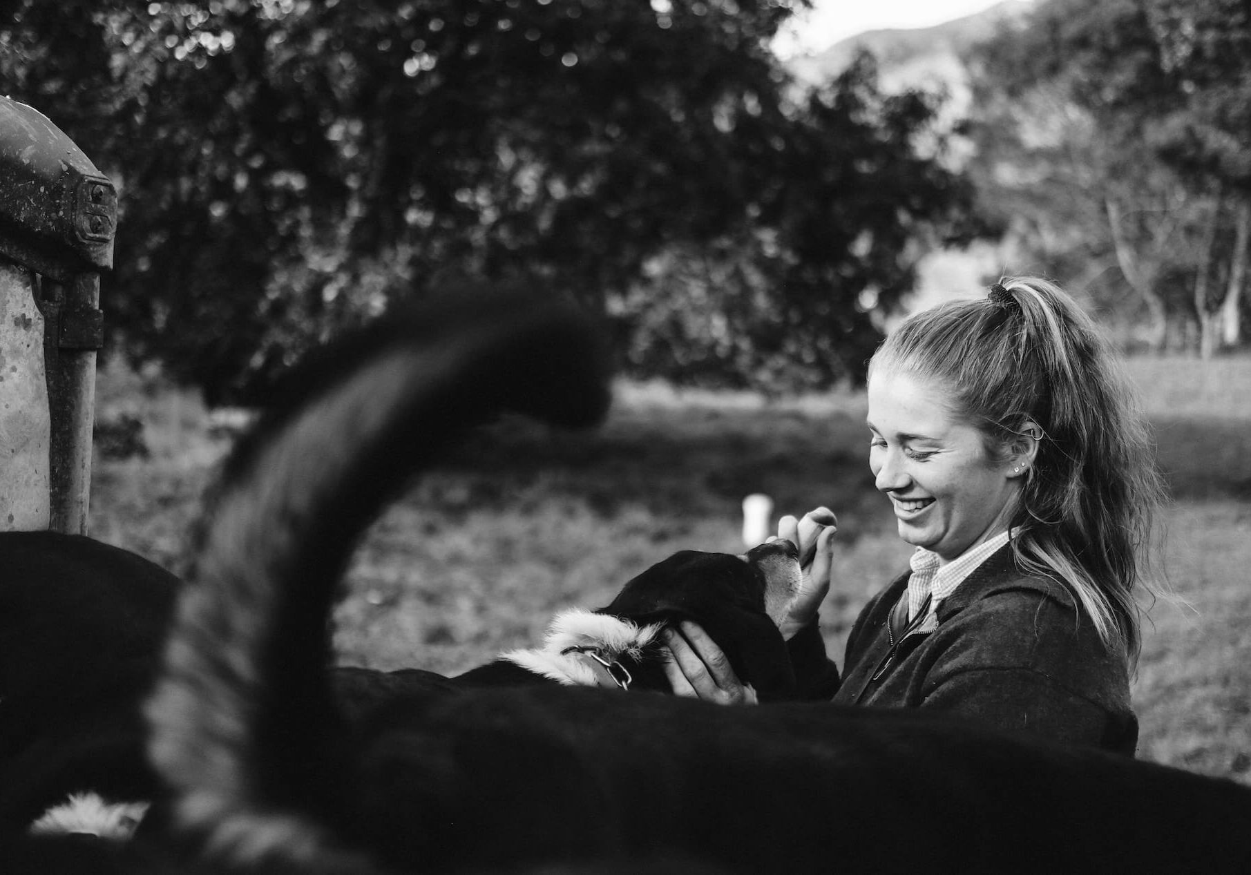 Black and white image of a young female shepherd with a dog.