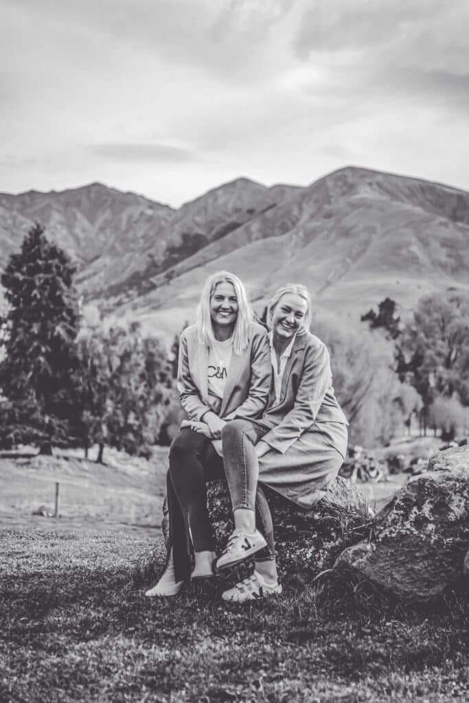 Black and white photo of two sisters sitting on a rock